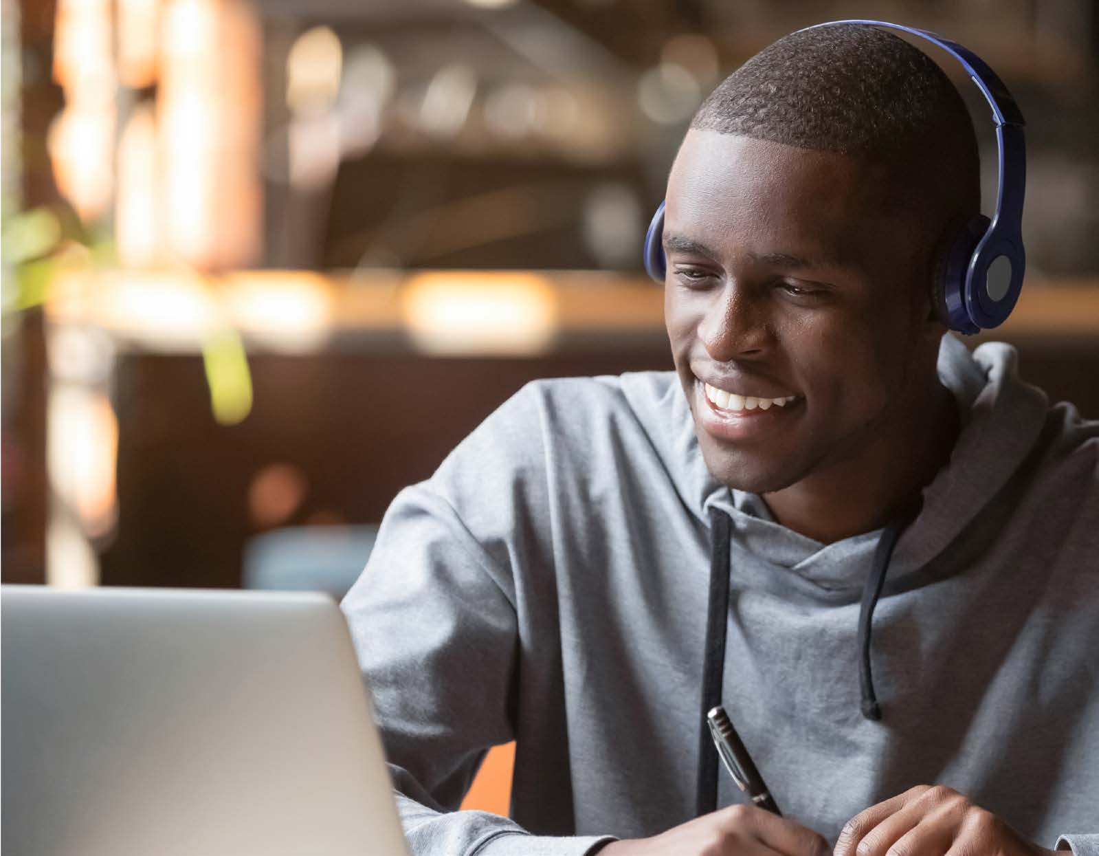 Young man with headphones writing in a notebook
